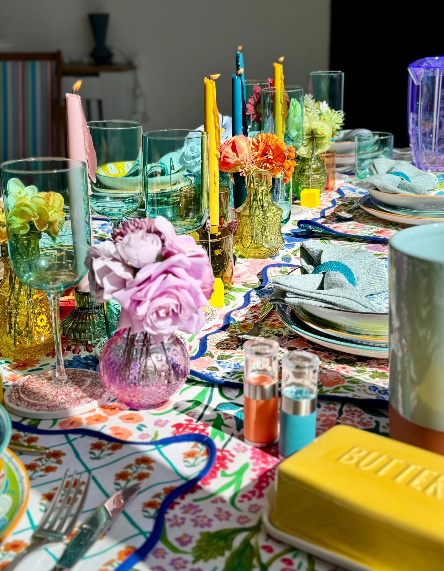 Richly styled dinner table with taper candles and colourful linens, perfect for hosting with a hired tablescape