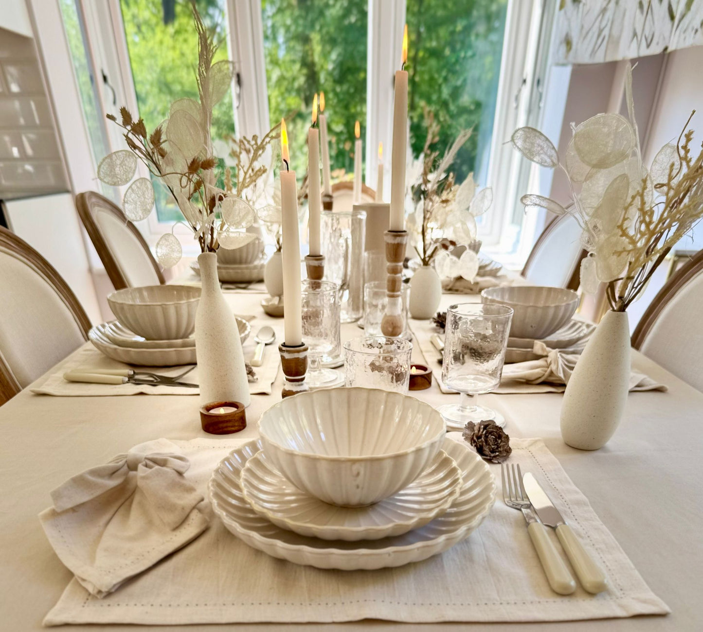 Clean, modern table setting featuring white ceramic plate,beige table linens, and silver/white cutlery